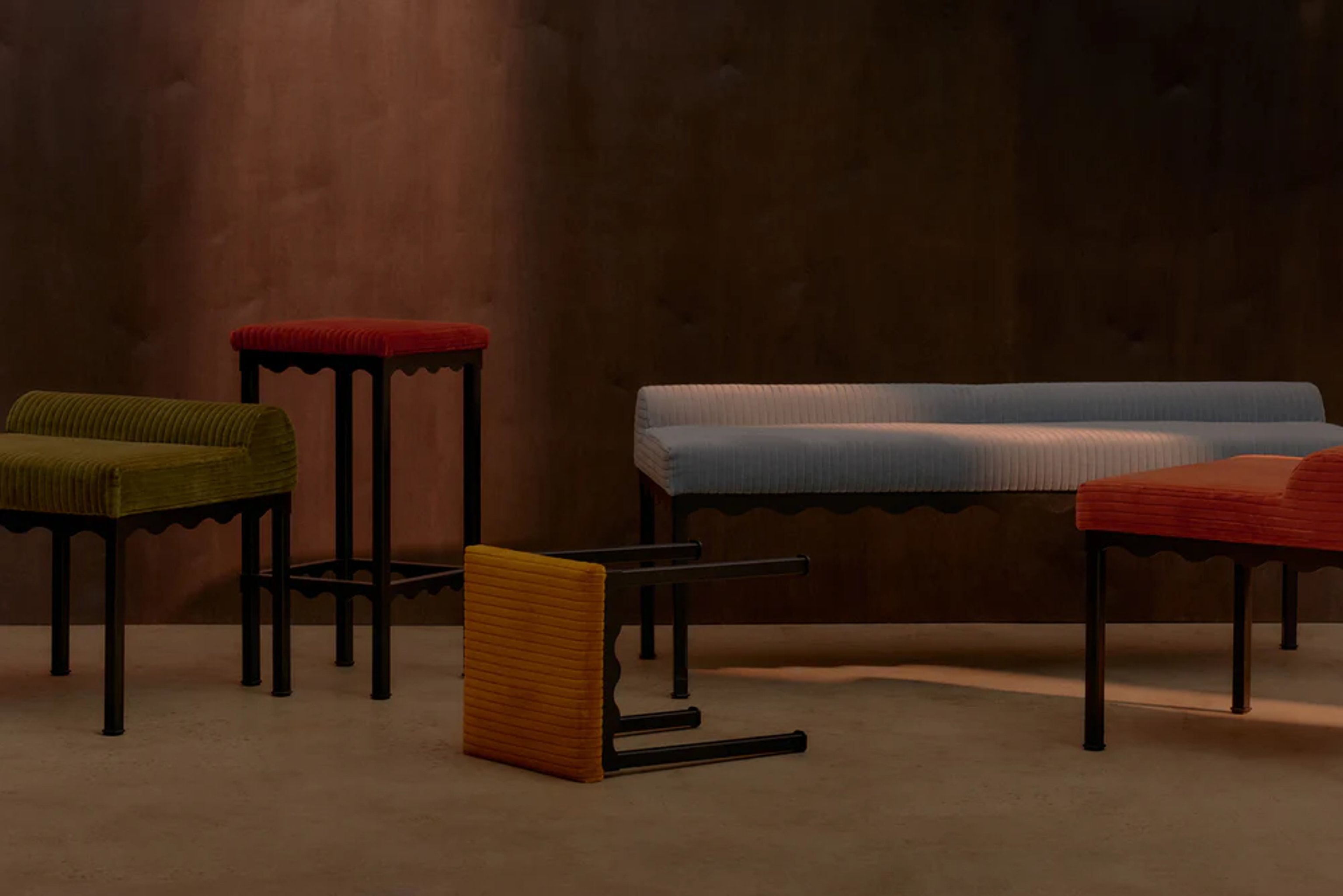 A series of upholstered bench seats and stools featuring wavy metal frames