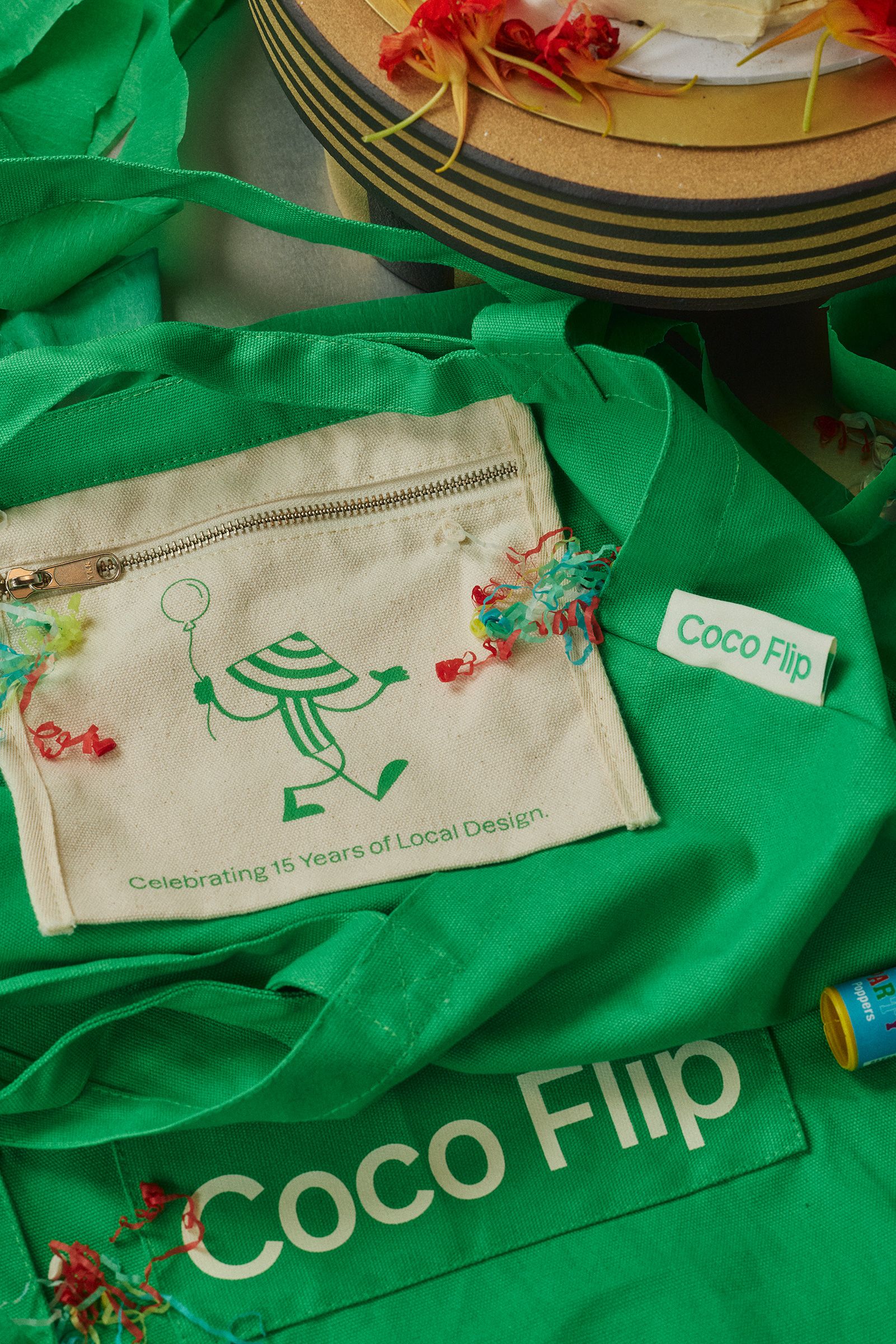 A green tote bag laying on a table with party popper streamers scattered on top