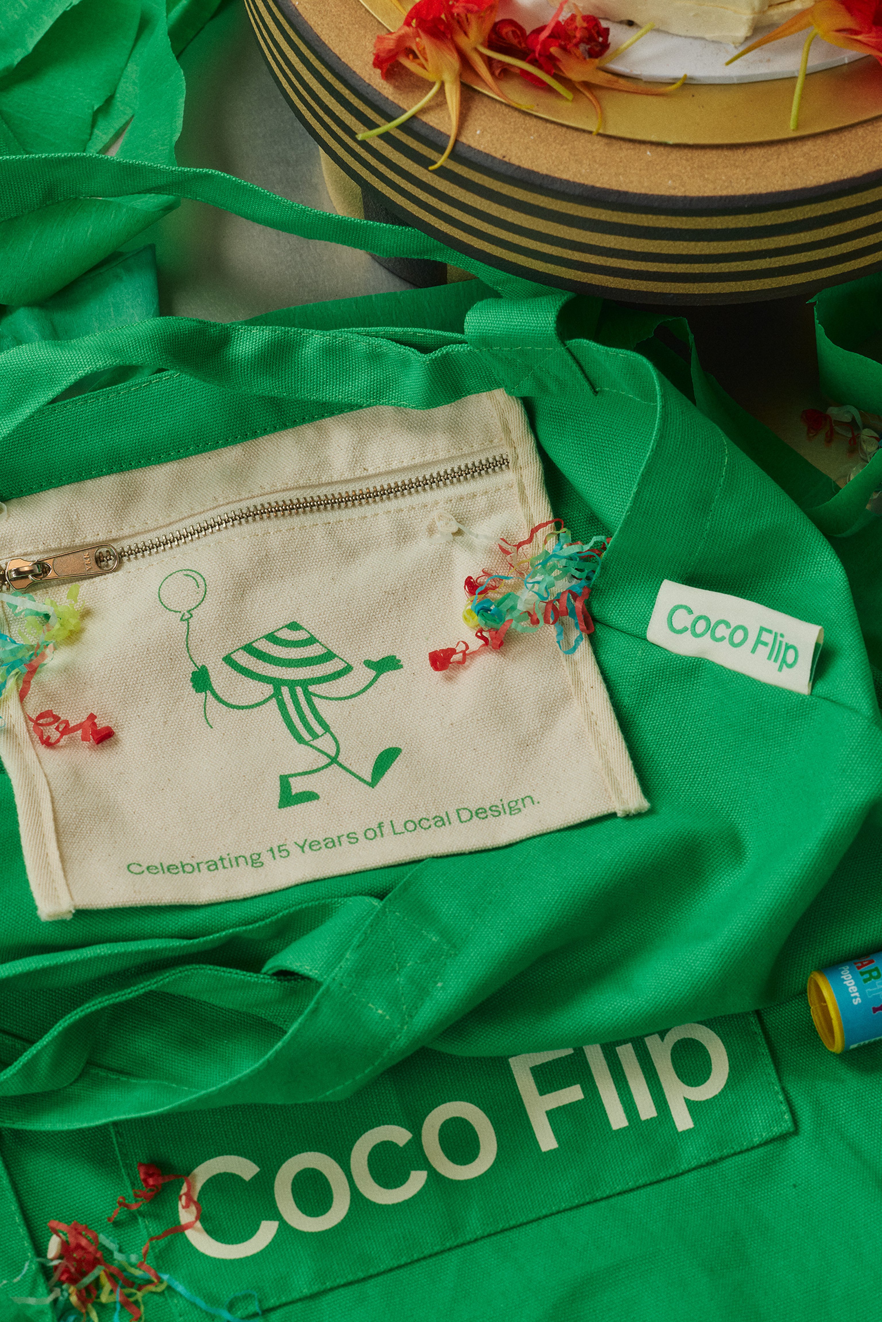 A green tote bag laying on a table with party popper streamers scattered on top