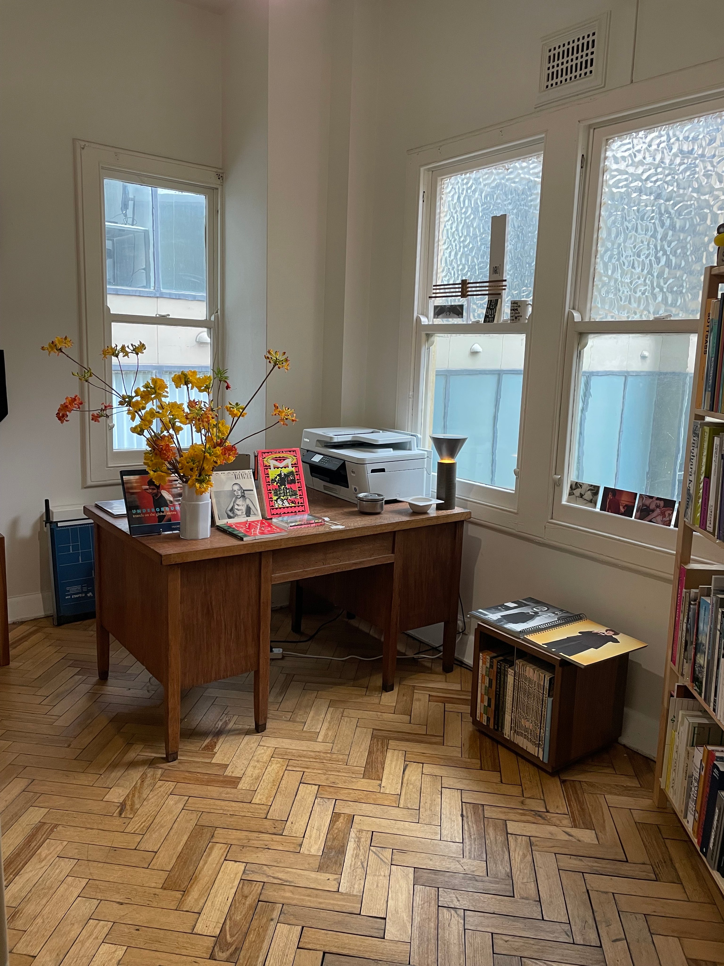A portrait of Jessica Lillico and Sean Fennessy sitting at a dining table. Behind them on a rendered brick wall is a large abstract artwork.