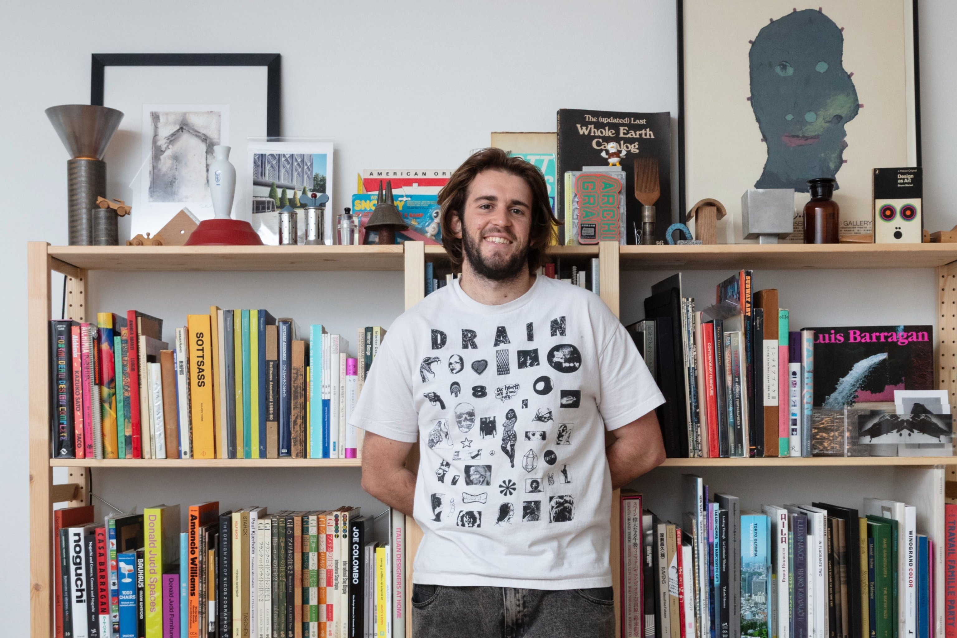 Sean Brickhill, founder of First Edition Library, photographed in front of a stacked shelf full or books and objects.