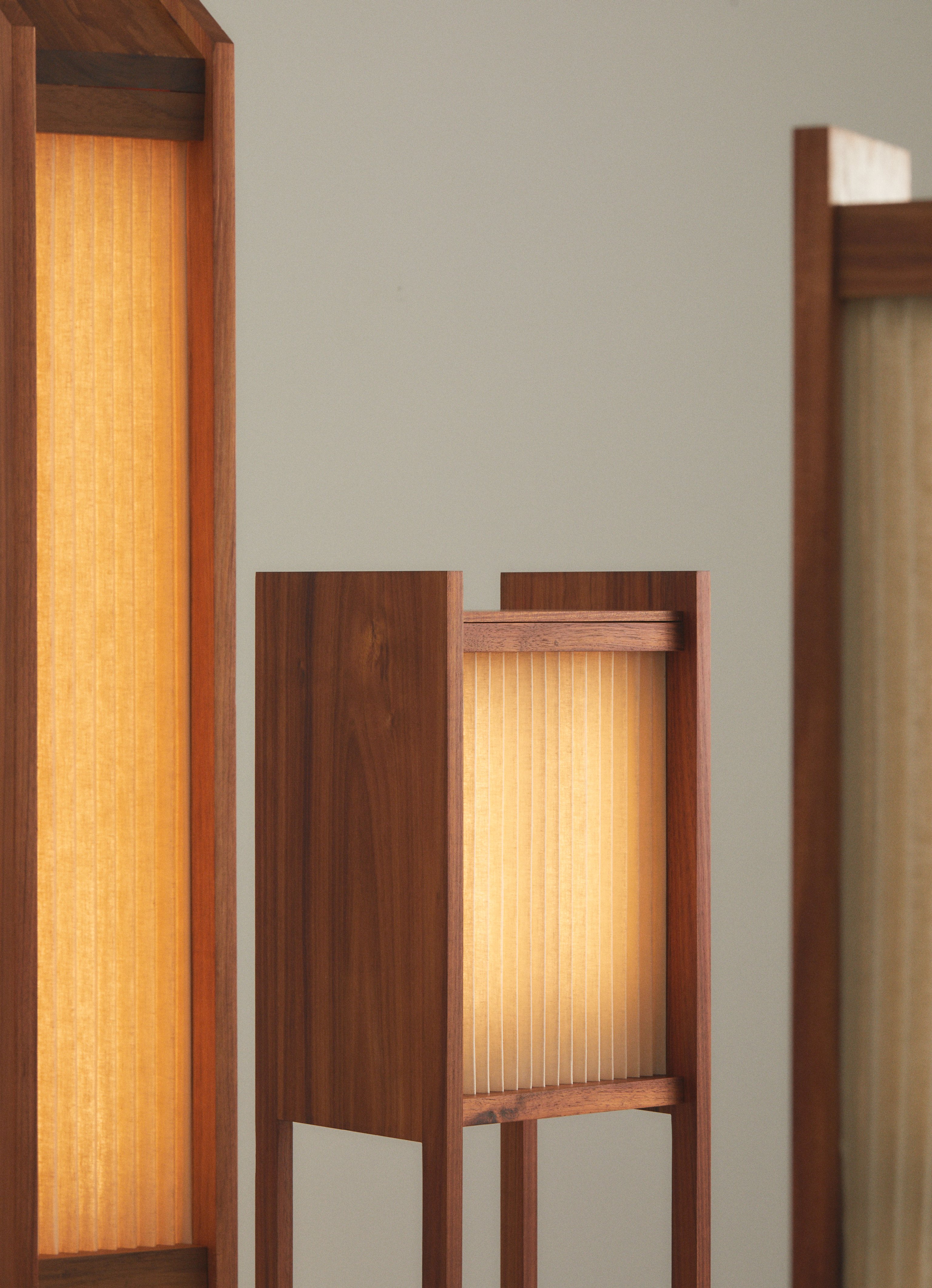 A collection of contemporary pleated linen light sculptures with a timber base, standing upright against a plain background.