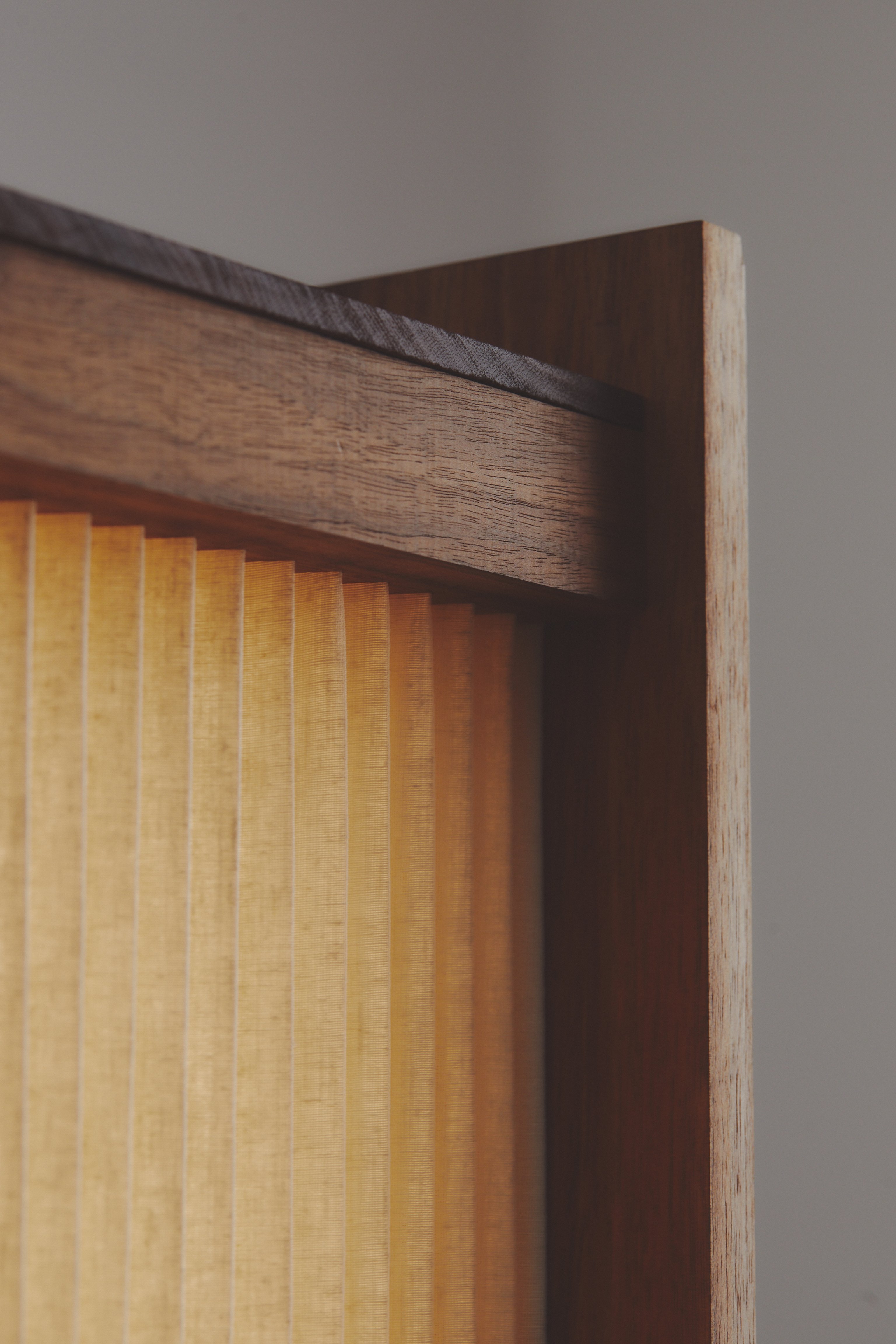 A contemporary pleated linen floor lamps with timber base and warm glow