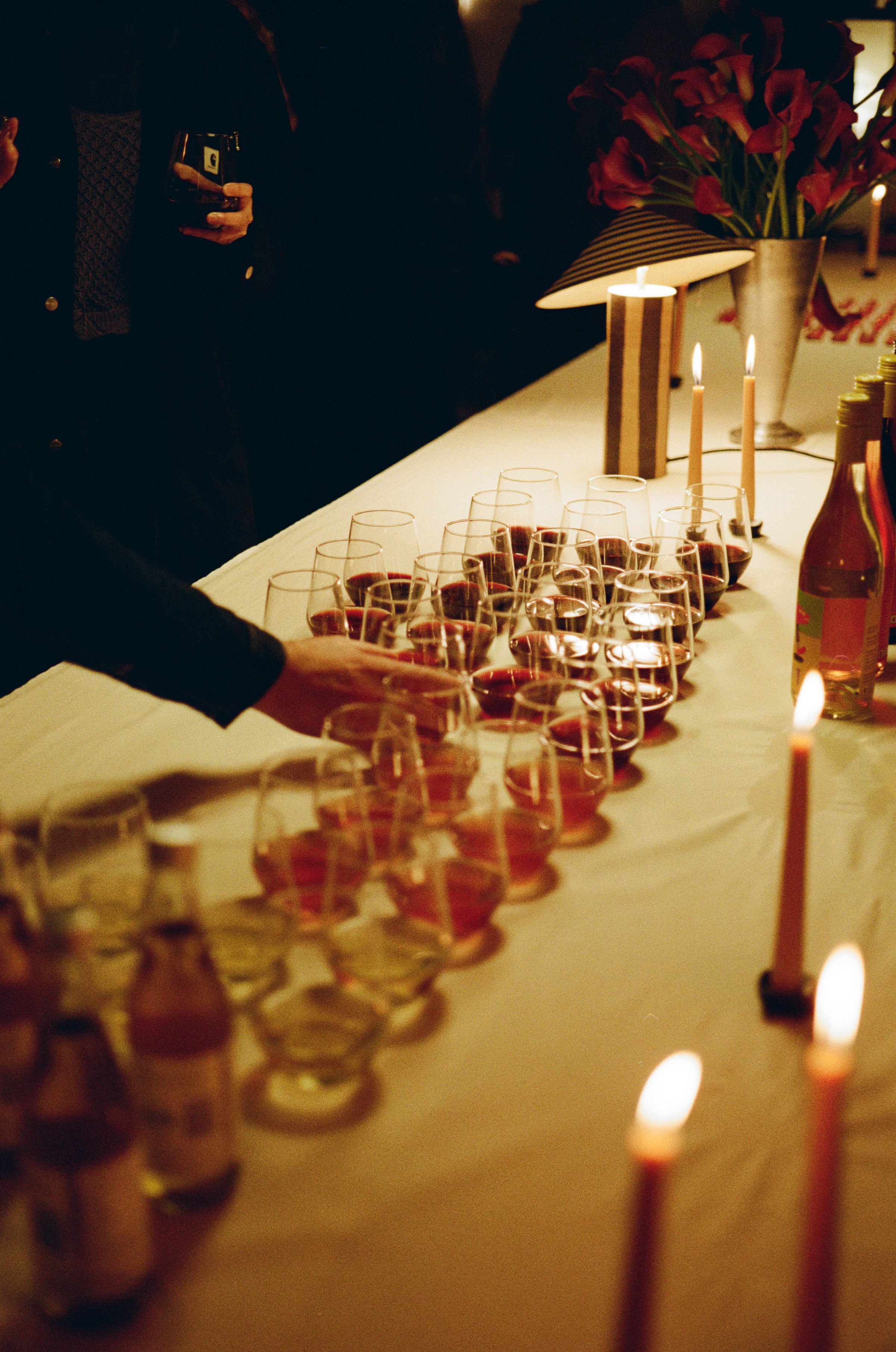 Row of filled glasses of wine, displayed in shades of pink, orange and red.
