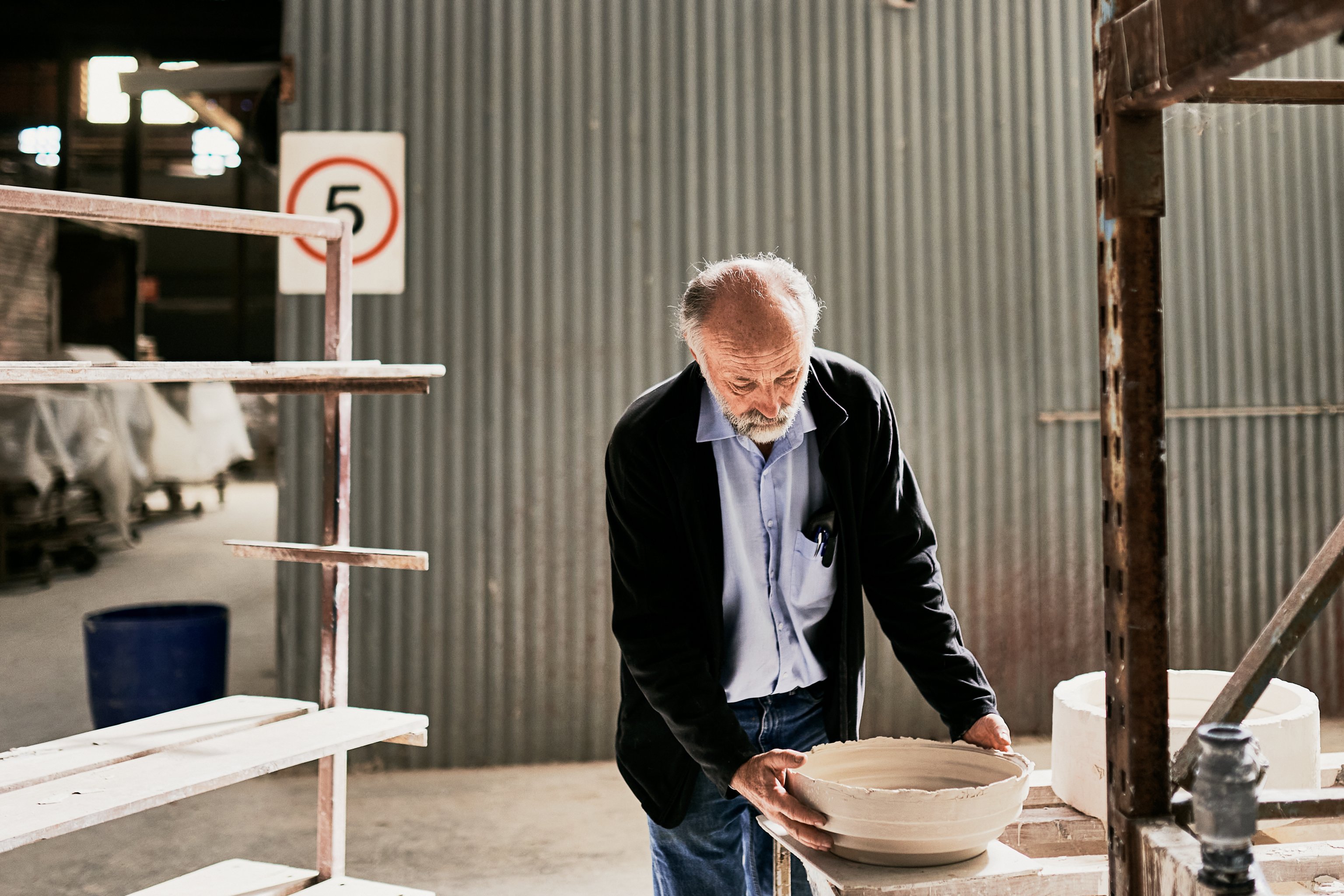 A man holds a ceramic slip casting mould in an open factory