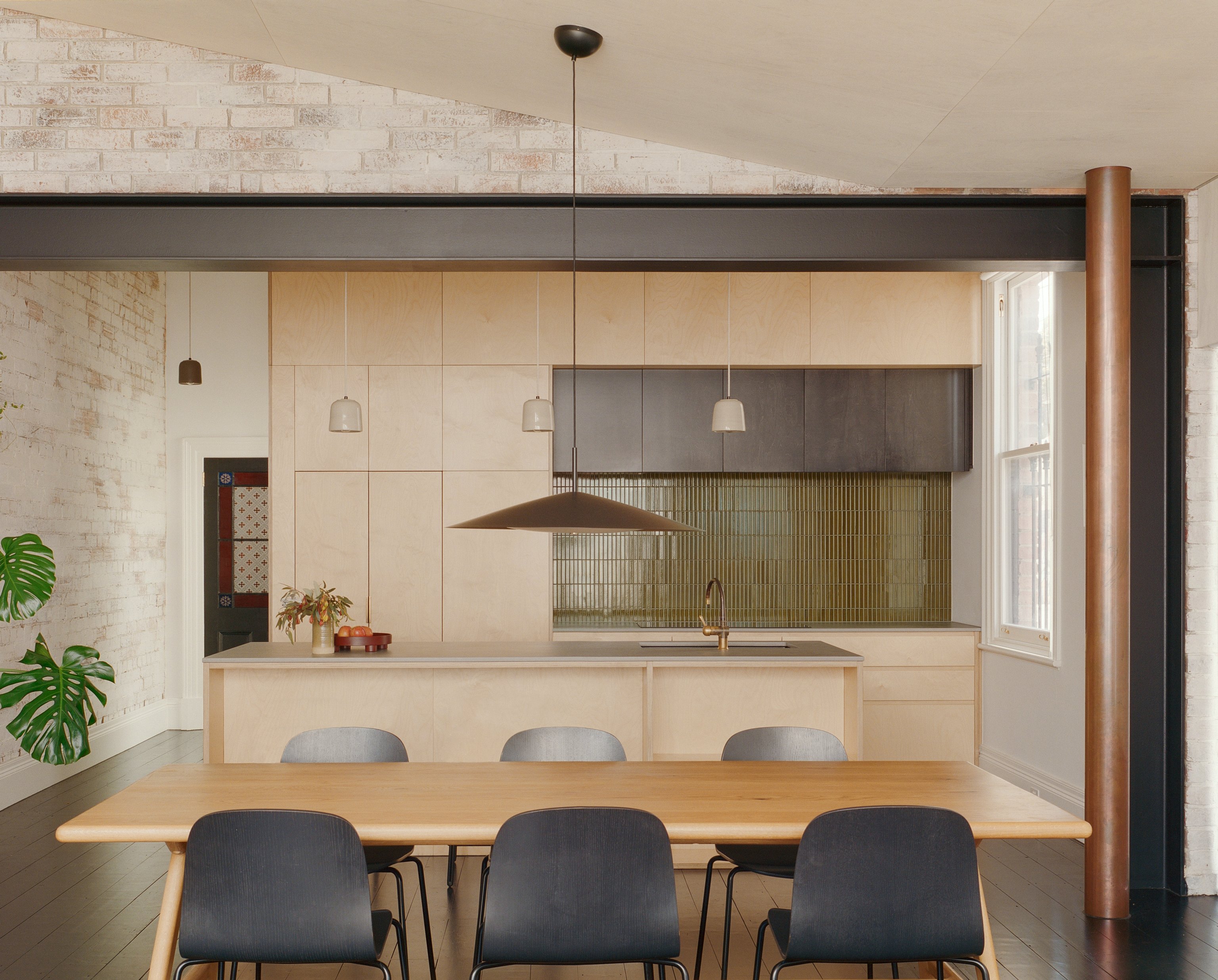 A kitchen dining room with a large dining table and black pendant light