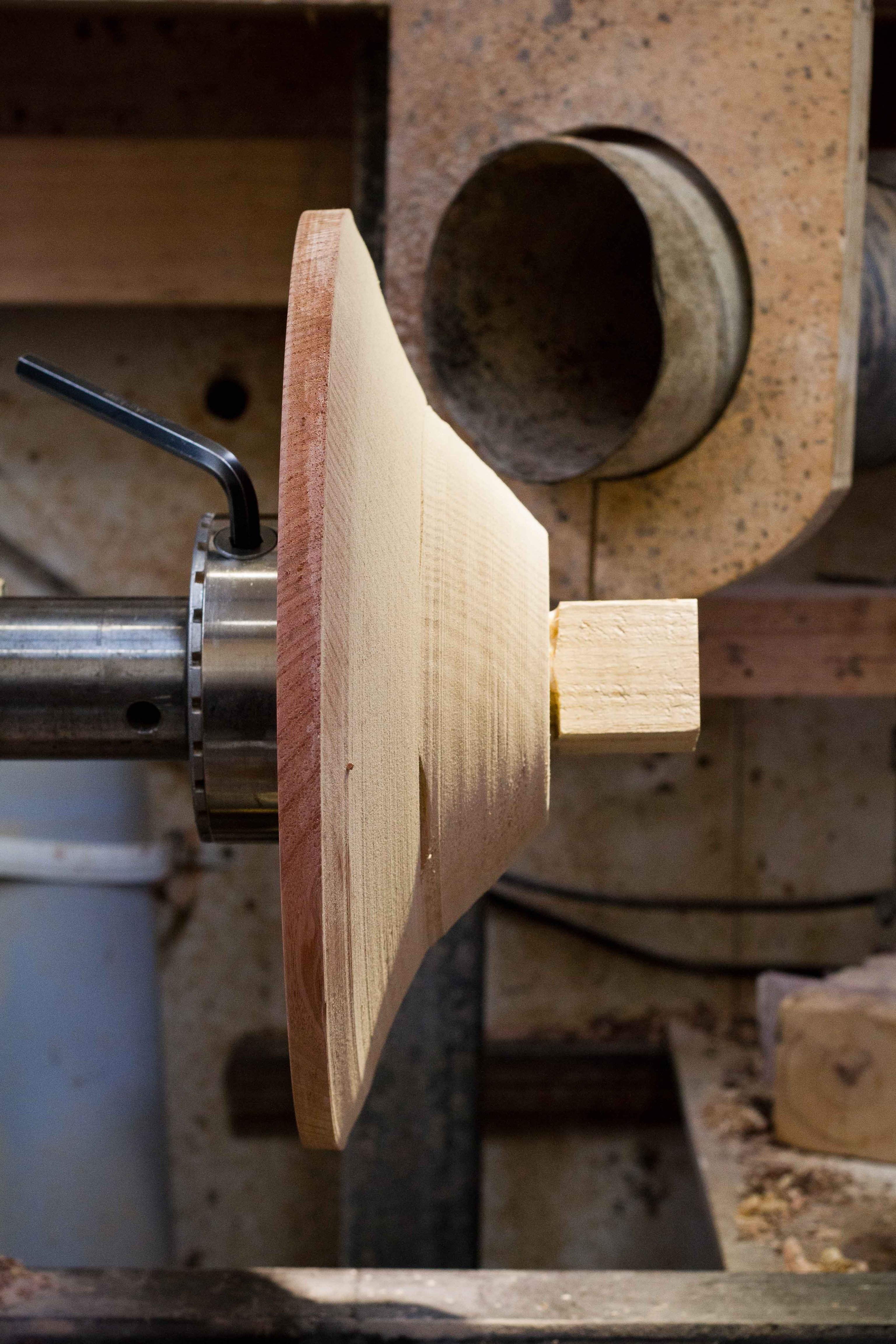 A laminated timber form attached to a lathe in a factory waiting to be turned.