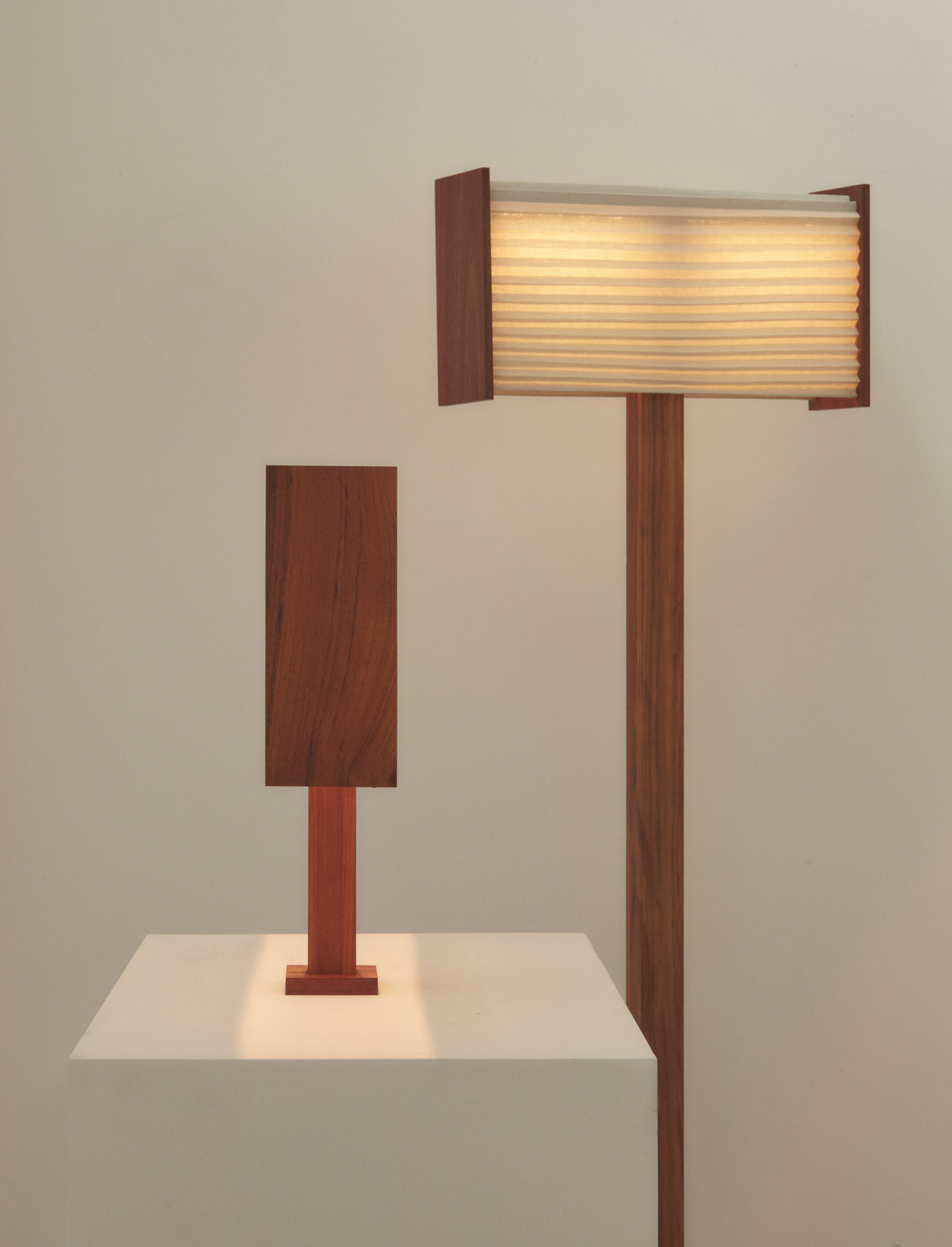 A table lamp on a plinth and a floor lamp with a timber structure and pleated linen frames