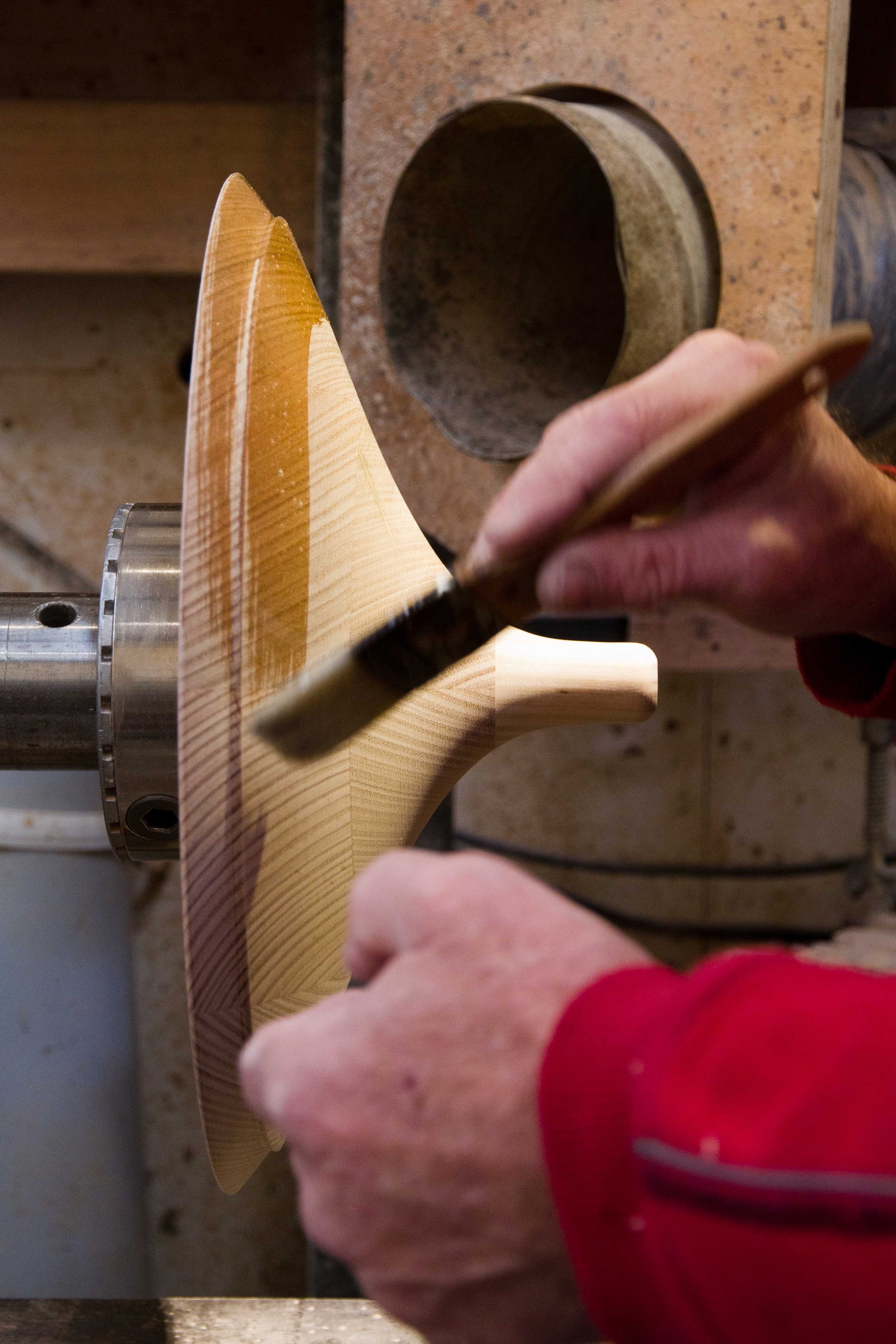 A man painting oil onto a timber Coco Pendant top.