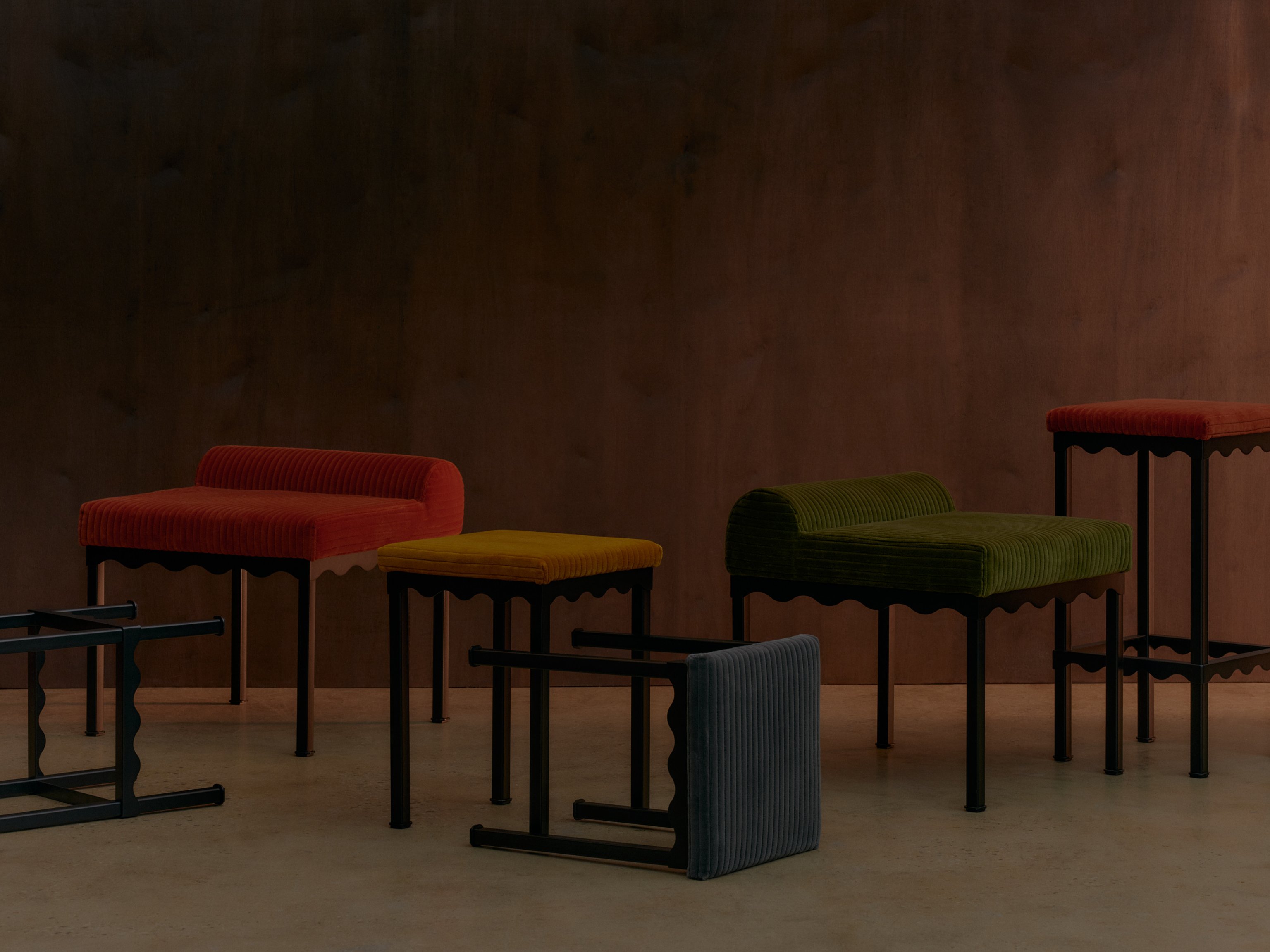 A series of upholstered bench seats and stools featuring wavy metal frames