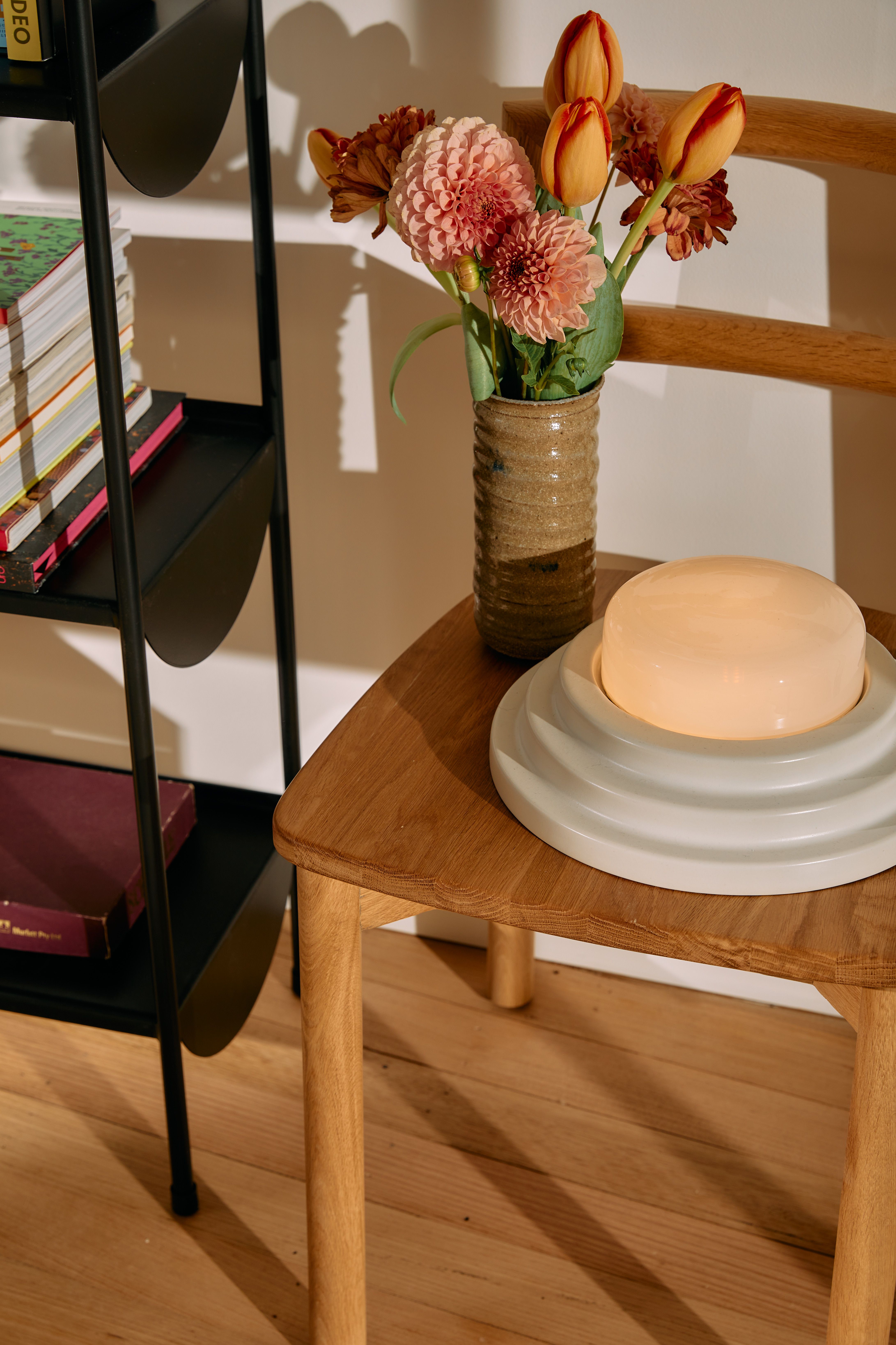 Honey Table Lamp sitting on a timber chair with a vase of flowers next to it