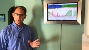 A man in a blue shirt presents data on a tiny screen