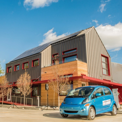A blue eco-friendly car parked in front of an efficient grey-and-red building