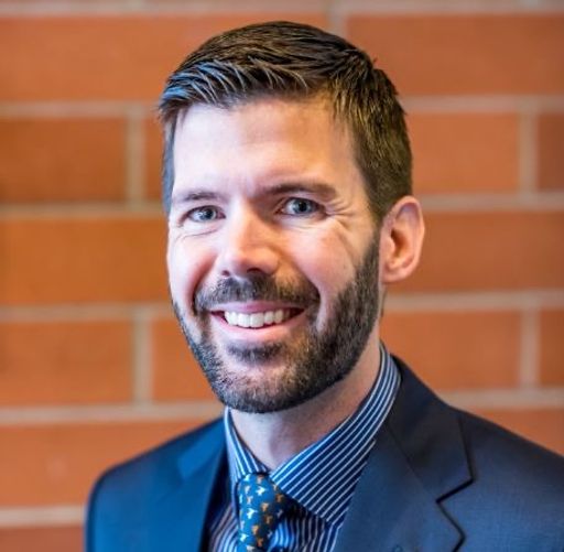 Scott Bollinger headshot against a red brick backdrop.