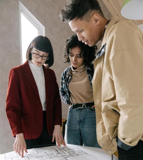 Three students look over some blueprints