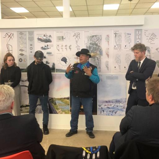 An indigenous man in a vest presents to a group of people