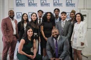 A group of 11 people pose for a photo in front of a REET Institute banner