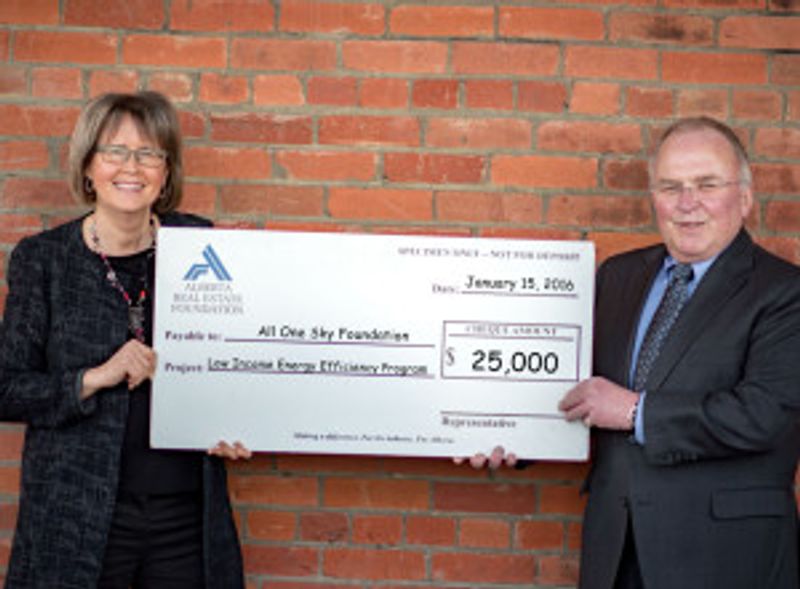 Two people hold up a novelty cheque for $25,000
