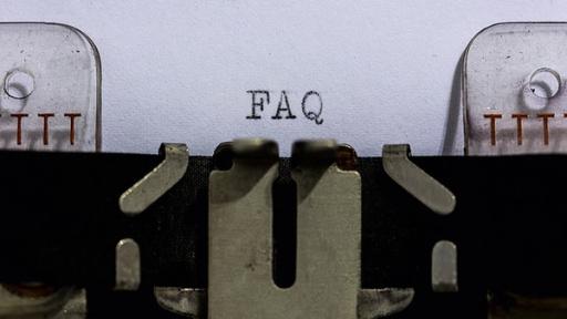 Macro photo of a typewriter typing the letters 'FAQ' in black ink on white paper.