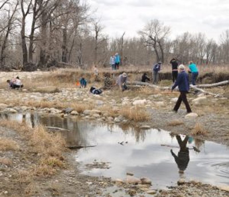 A group of people clean up half-dried riverbed