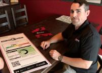 A man in a black shirt sits next to a large 'EnerGuide' sign