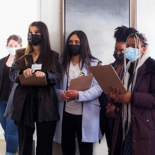 A group of four women reading from clipboards