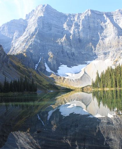Sunny mountain lake with a bright reflection of a mountain.