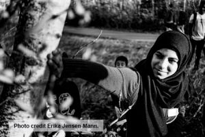 A woman touches a tree in greyscale. Photo credit reads "Erika Jensen-Mann"