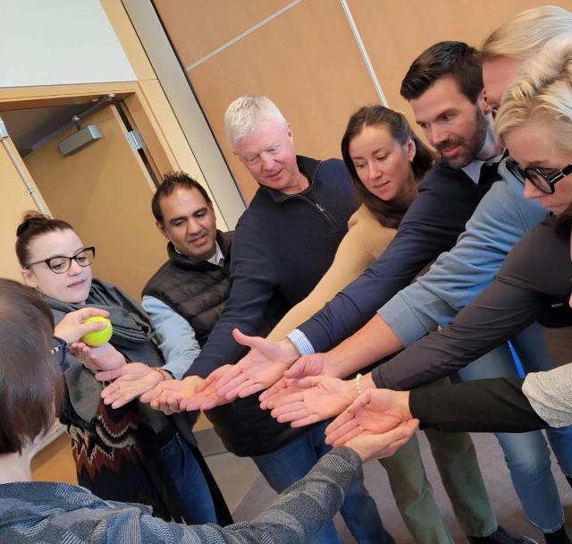 A business team participates in a team-building exercise with a tennis ball