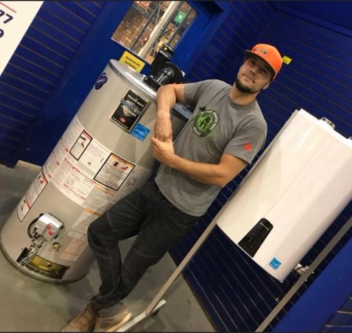 A man in an orange hat leans his right arm on a high-efficiency water heater