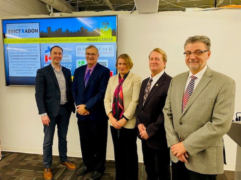 Five people pose in front of a presentation screen reading 'Evict Radon'