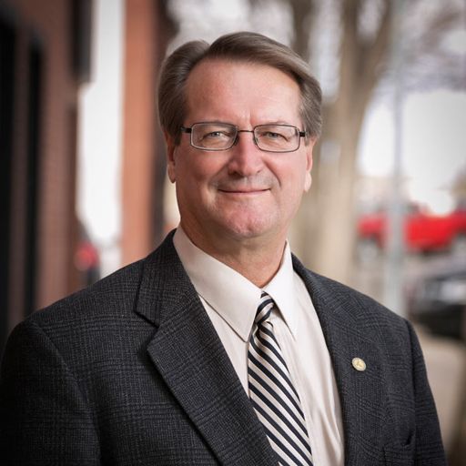 Headshot of Jim Saunders standing outside with a blurry backdrop of trees behind him