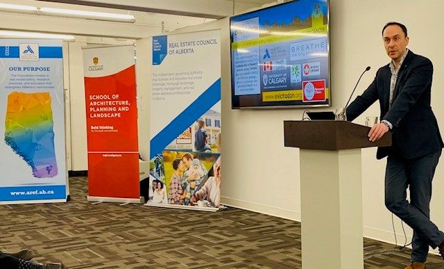 A man in a suit jacket presenting at a podium