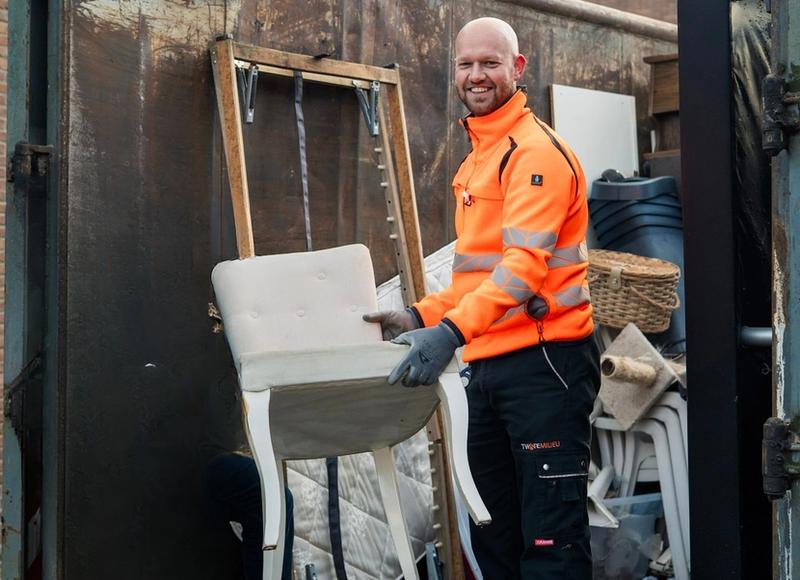Medewerker Twente Milieu zet stoel in een container