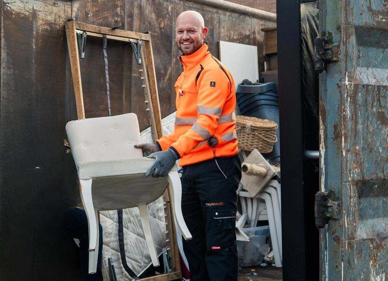 Medewerker Twente Milieu zet stoel in container