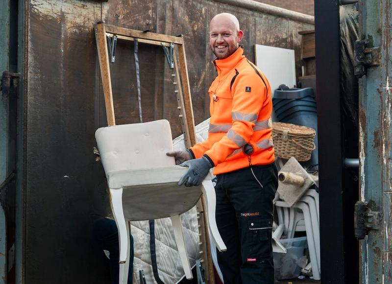 Medewerker Twente Milieu zet stoel in een container