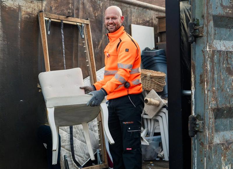 Medewerker Twente Milieu zet stoel in container