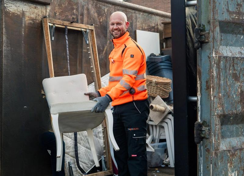 Medewerker Twente Milieu zet stoel in een container