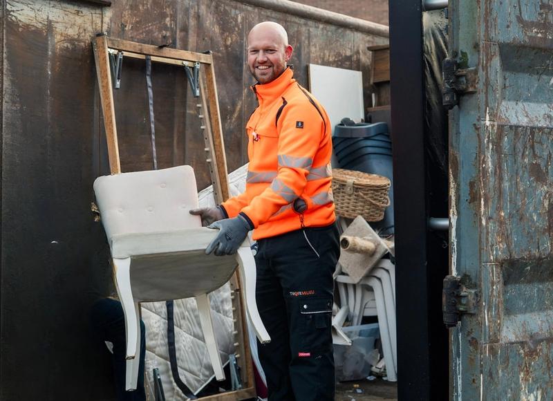Medewerker Twente Milieu zet stoel in container