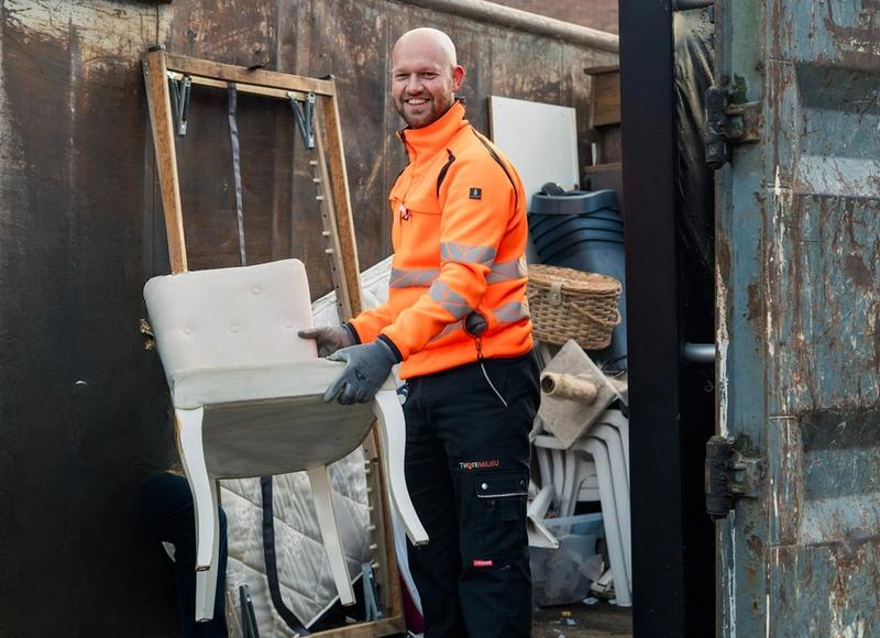 Medewerker Twente Milieu zet stoel in container