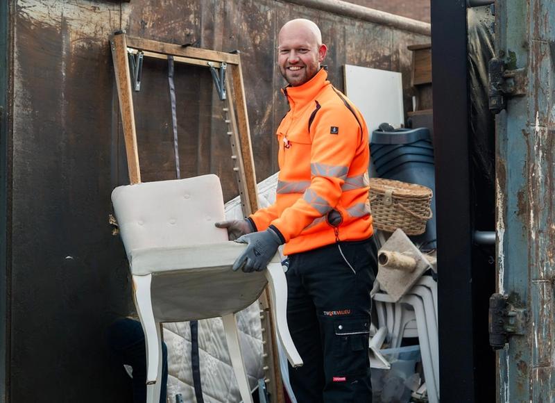 Medewerker Twente Milieu zet stoel in container