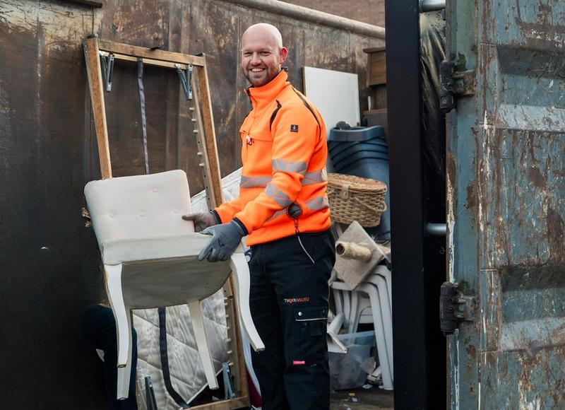 Medewerker Twente Milieu zet stoel in container