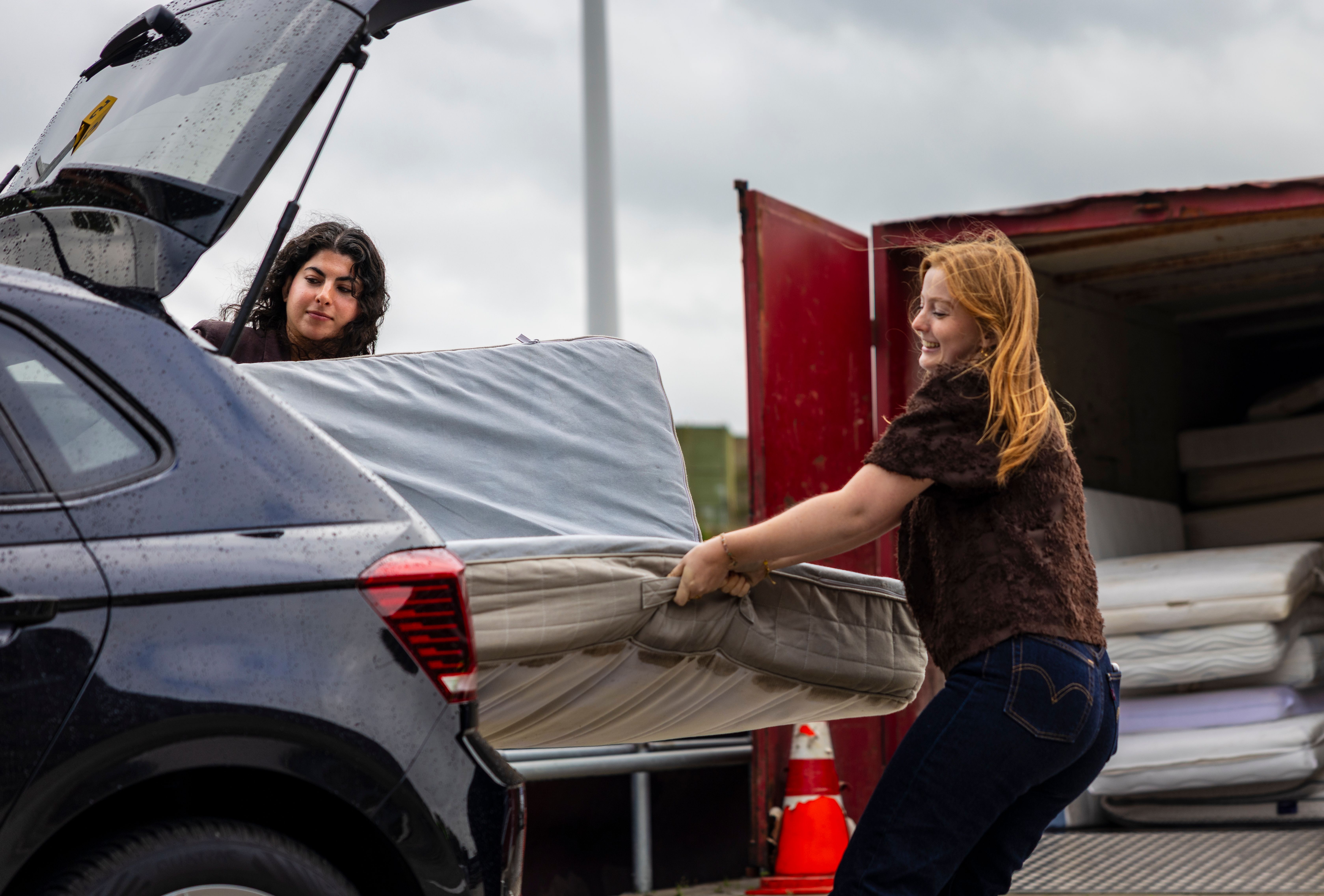 Twee dames halen een matras uit een auto op het afvalbrengpunt