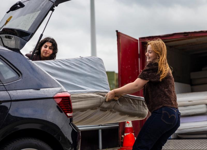 Twee dames halen een matras uit een auto op het afvalbrengpunt
