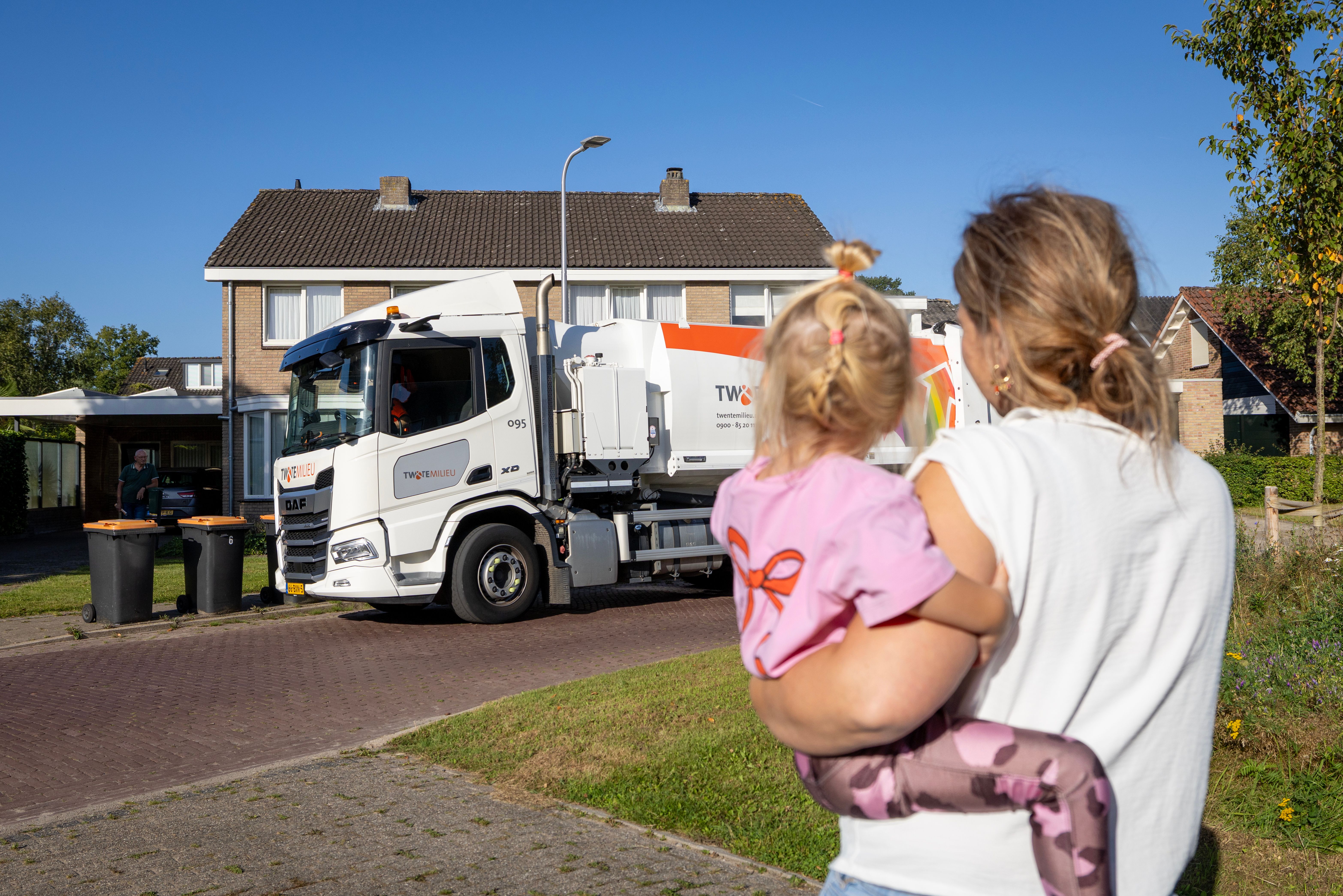 Moeder en kind zwaaien naar de vuilniswagen.