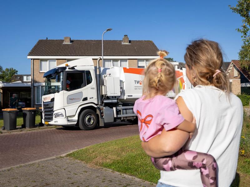 Moeder en kind zwaaien naar de vuilniswagen.