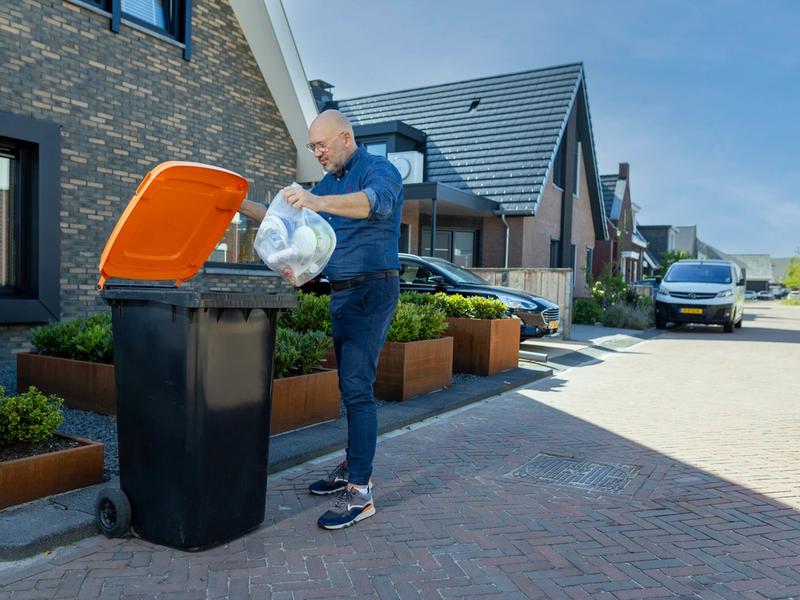 Inwoner gooit afval in verpakkingencontainer