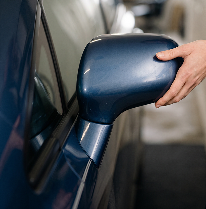 Close-up of person evaluating car mirror condition to assess vehicle value and overall car condition