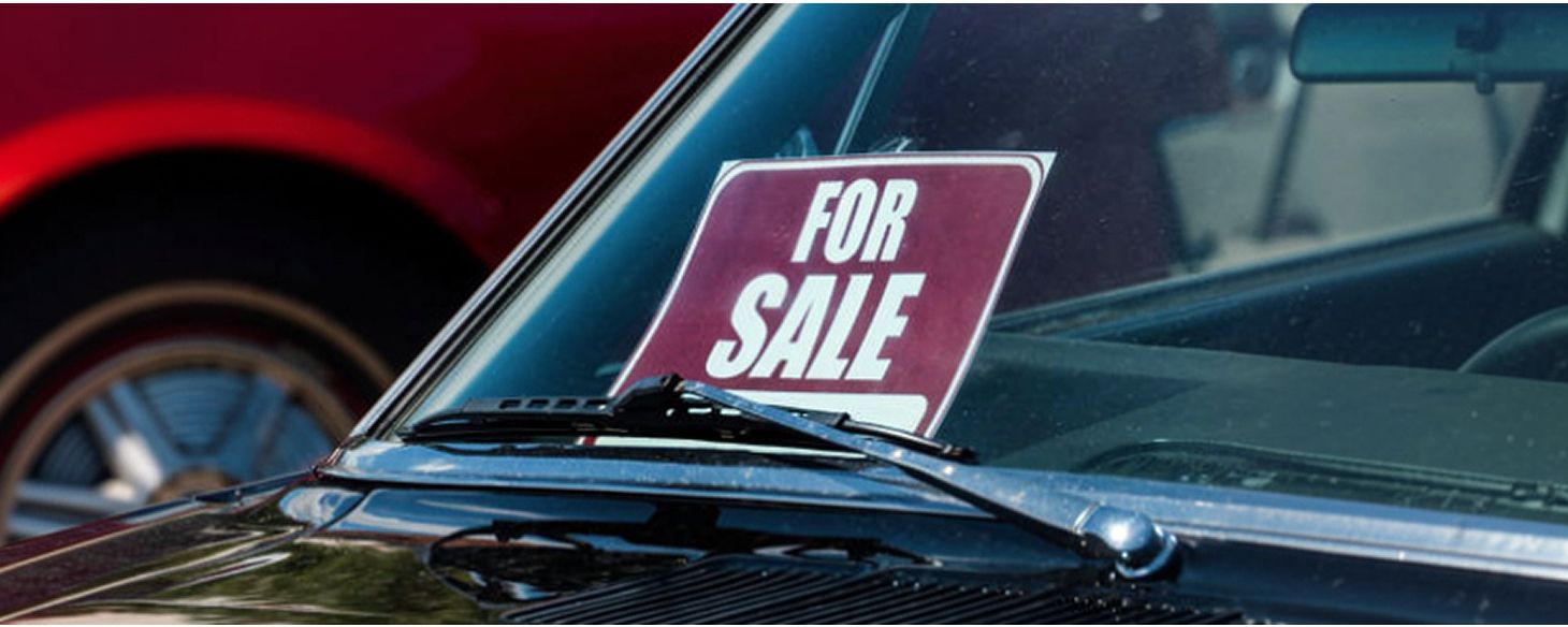 For Sale sign displayed in the windshield of a car parked for private sale