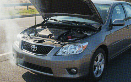 Toyota sedan with a blown engine, hood open, and smoke coming from the engine on the roadside.